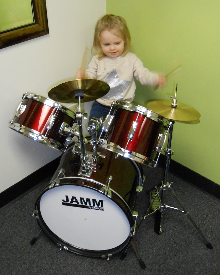 A little girl plays drums